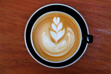 Top view of coffee latte art with tulip pattern on top on rustic wooden table bar