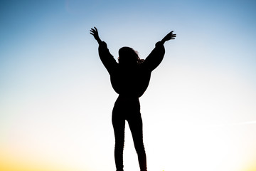 Fototapeta na wymiar Silhouette of an attractive young woman jumping on wall during sunset. Energy concept.