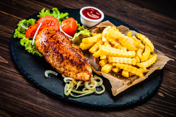 Grilled chicken fillet with french fries on wooden table