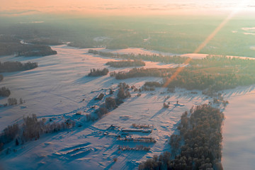 Aerial view winter sunrise over snow-covered space of the forest territory. Aircraft photography from above.
