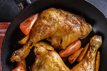 Roasted chicken legs with potato wedges and tomatoes