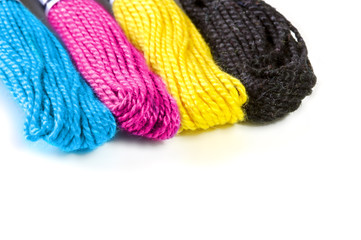 Four sawing silk threads in the prepress colors cmyk with white copy space for text.