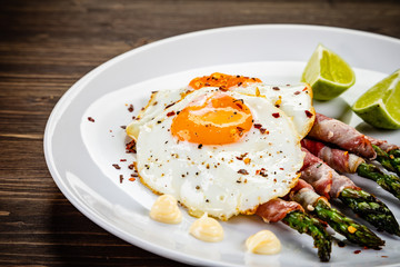 Fried egg with asparagus on white background
