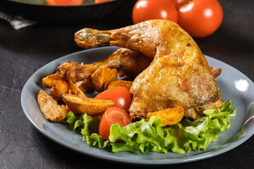 Roasted chicken legs with potato wedges and tomatoes