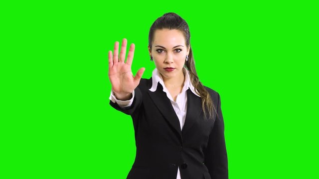 Young serious beautiful woman showing stop sign. Prohibition symbol. Isolated on green screen chroma key background.