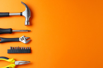 Hammer, pliers, screwdriver on an orange background, top view, a place for an inscription - obrazy, fototapety, plakaty