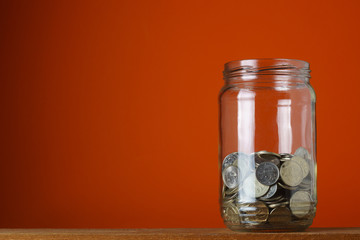 Glass jar with Russian metal rubles, on an orange background