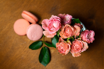 pink roses in a vase with macaroons