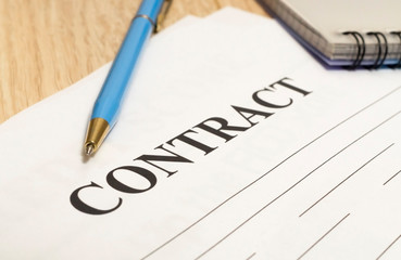 Contract with pen and notebook on wooden table.
