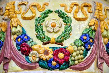 Fototapeta na wymiar Multi-colored ceramic ornament of flowers, fruits, vegetables, cones, leaves