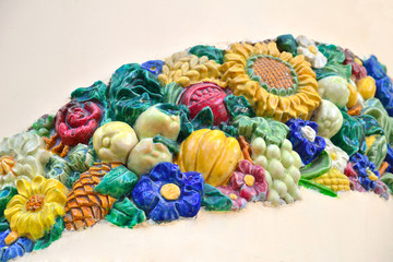 Multi-colored ceramic ornament of flowers, fruits, vegetables, cones, leaves
