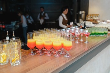 Cocktail of different fruits and alcohol on a wooden table.