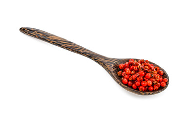 dried pink peppers in wood spoon isolated on white background