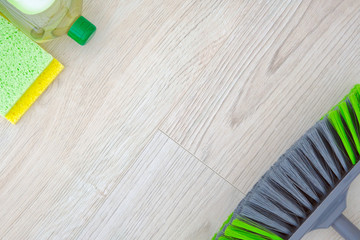 Set of green cleaning products on wooden background. Detergent in plastic bottle, sponges and brush. Сleaning accessories. Top view. Copy space.