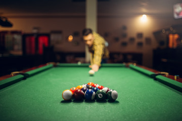 Male billiard player with cue aiming at the table - obrazy, fototapety, plakaty