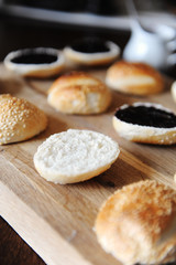 Sesame burgers buns split in half on wooden cutting board. Dark berry sauce on top. Cooking process