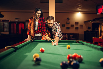 Family couple plays in billiard room