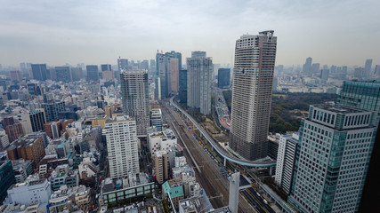 Fototapeta premium Arial view of busy Tokyo city showing dense highrise buildings, train tracks, and highways with background sky