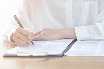 Beautiful Asian woman is smiling.Asian women work with gray laptops on the sofa in the room in the morning.She is drinking coffee.White coffee cup.Lady sitting in the white room.