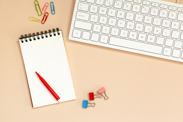 Workplace Blank spiral notebook with keyboard on table. Top view