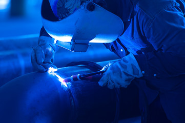 Worker Blacksmith wearing protective mask Welding metal piping using tig welder in workshop