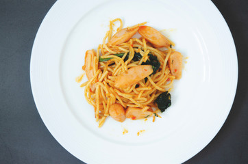 Spaghetti with sausage, Stir-fried sausage, Italian food.Spaghetti with red sauce, white plate on the table in the morning restaurant.
