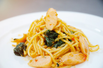 Spaghetti with sausage, Stir-fried sausage, Italian food.Spaghetti with red sauce, white plate on the table in the morning restaurant.