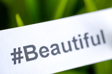 Popular hashtag "beautiful" printed on paper on a green background.