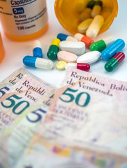 Fototapeta na wymiar Medicines next to banknotes of Venezuela, shady deal of medication in full crisis of country of Latin America, conceptual image, composition vertical