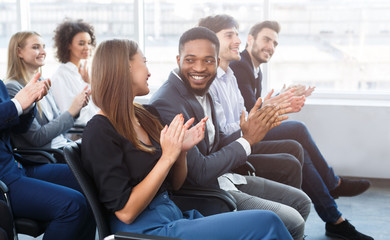 Happy business colleagues clapping hands at conference