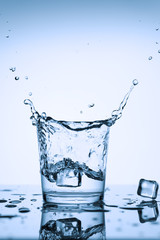 Splash in a glass of water. Splashes of clean water in a glass with ice, on a white background.