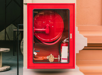 Fire extinguisher and fire hose reel in wall corridor
