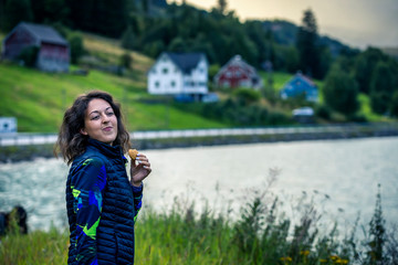 Portrait of young happy woman eating cookie after hiking.