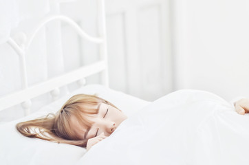 On the bed in the white room.Beautiful woman sleeping in the bedroom.Asian girl sleep well.Sleeping in a white room makes you feel comfortable.Warm tone.