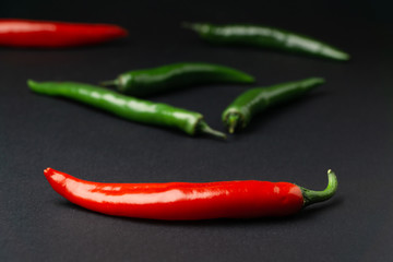Green and red chili peppers on black background. Hot spicy food symbol.