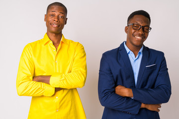 Two young happy African businessmen smiling with arms crossed together