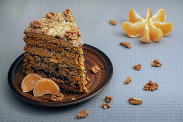 A large piece of homemade cake on a ceramic plate with nuts and mandarin