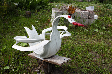 Handmade from an old car tire in the form of a white swan in green grass. © Борис Ряузов