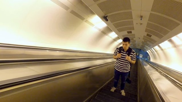 Young man on empty escalator going up from a subway