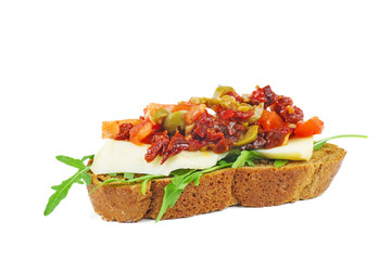 Piece of rye bread with cheese, dried tomatoes, olives and vegetables isolated on white background