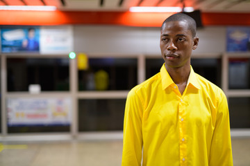 Young bald African businessman thinking and waiting in the subway train station