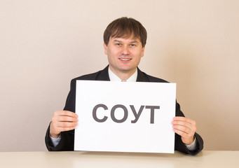 Employee with a sign SOUT at the table in the office