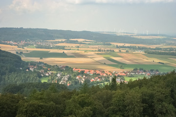 Fototapeta na wymiar Typical german landscape with a village, hills, forest and wind turbines in the background