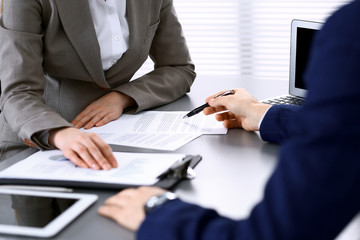 Business people and lawyer discussing contract papers sitting at the table, hands close-up. Teamwork or group operations concept