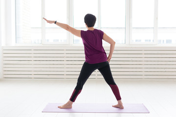 Obraz premium Sport, yoga, people concept - Sporty middle-aged woman practicing yoga indoors