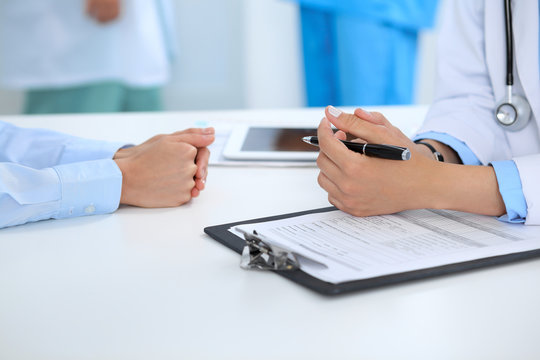 Doctor and patient discussing something, just hands at the table, white background