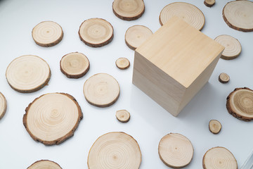 Pine tree cross-sections with annual rings and wooden cube on plane white surface. Lumber piece...