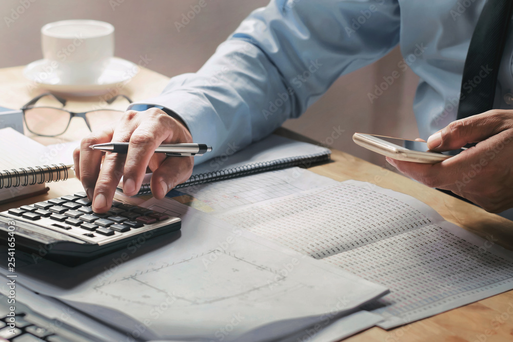 Poster businessman working on desk in office using calculator and mobile