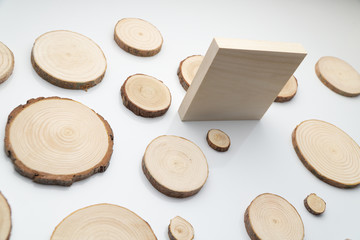 Pine tree cross-sections with annual rings and wooden square on white surface. Lumber piece close-up shot.