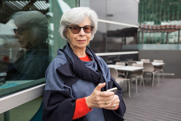 Portrait of stylish senior woman using mobile phone outdoors